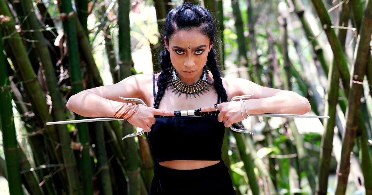 A powerful portrait of a woman holding sais in a bamboo forest, showcasing strength and style.
