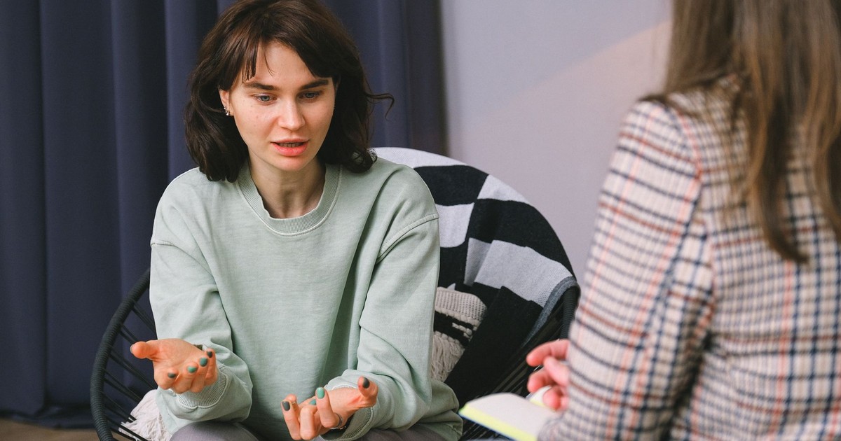 Calm female sitting on armchair and giving interview to concentrated woman in light room