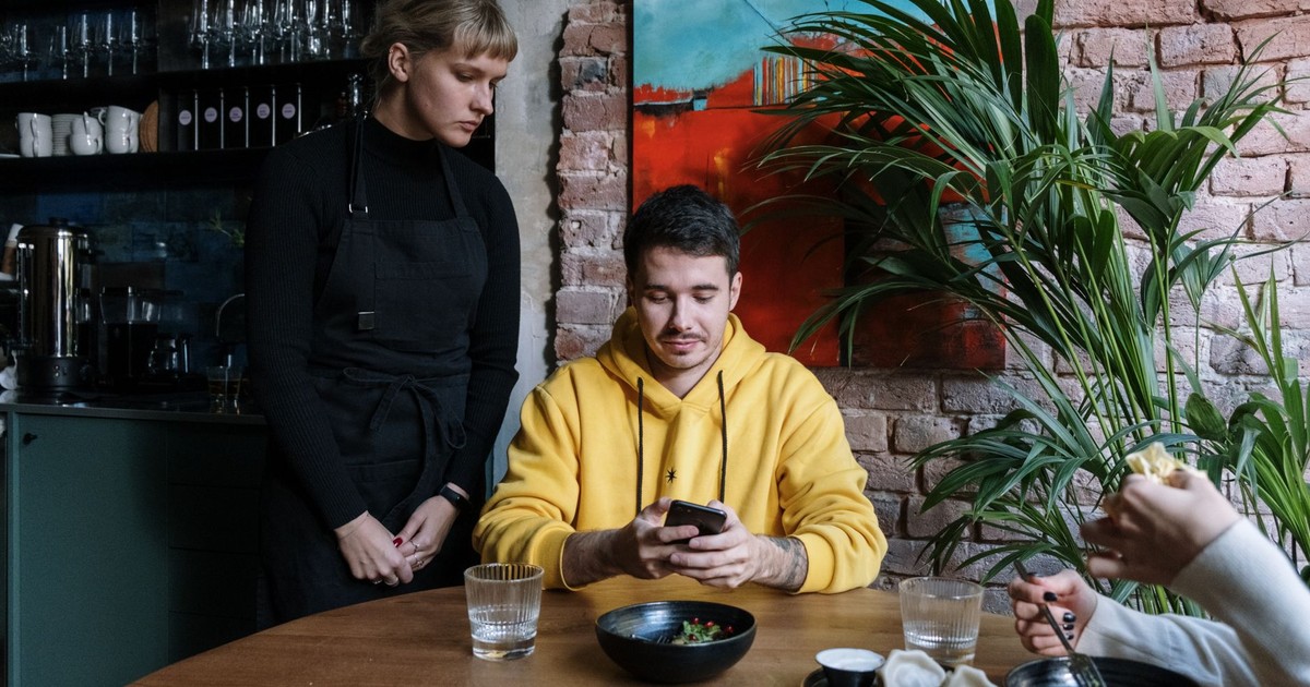Two people interacting in a stylish café with art and greenery.