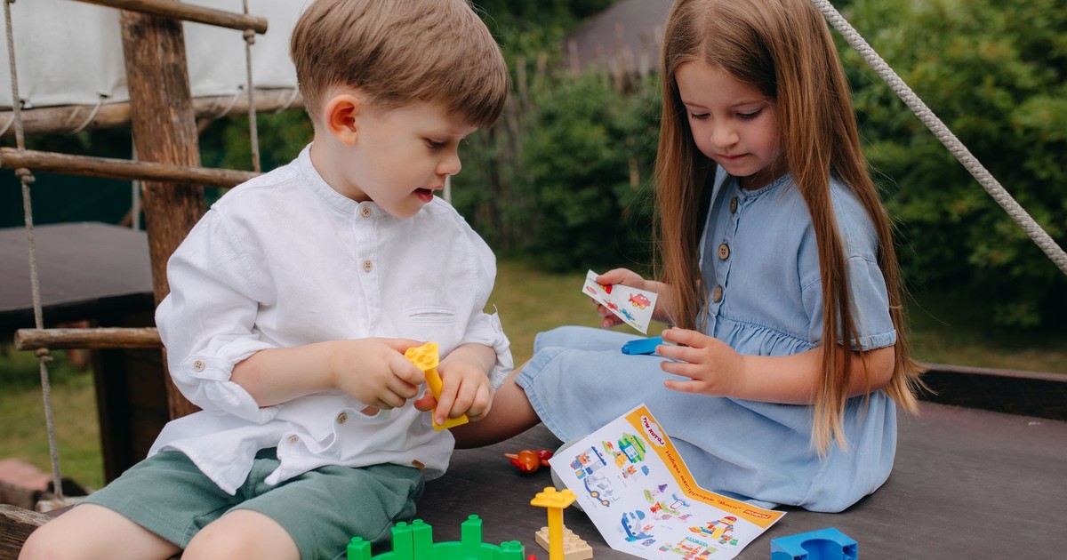 Two children enjoy playing with colorful building blocks on a sunny day.
