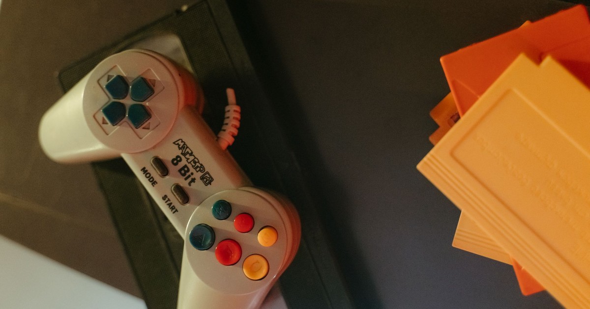 A vintage 8-bit game controller with colorful buttons next to classic game cartridges.