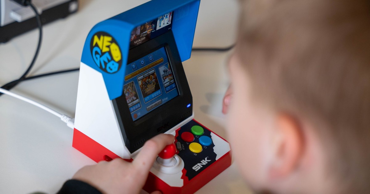 A child engaging with a Neo Geo mini arcade machine, enjoying retro gaming indoors.