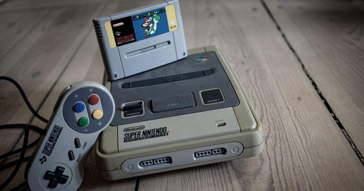 From above of aged video game console with cassette and controller with colorful buttons on wooden surface