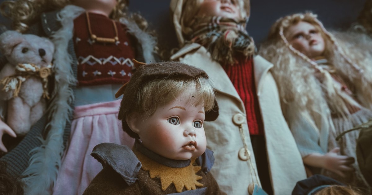 A collection of vintage porcelain dolls with intricate clothing, creating an eerie atmosphere.