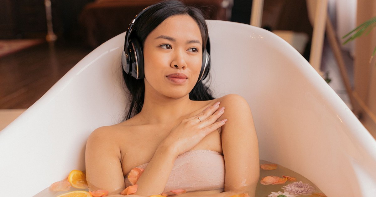 A serene moment of self-care with a woman in a tub surrounded by petals and citrus slices.