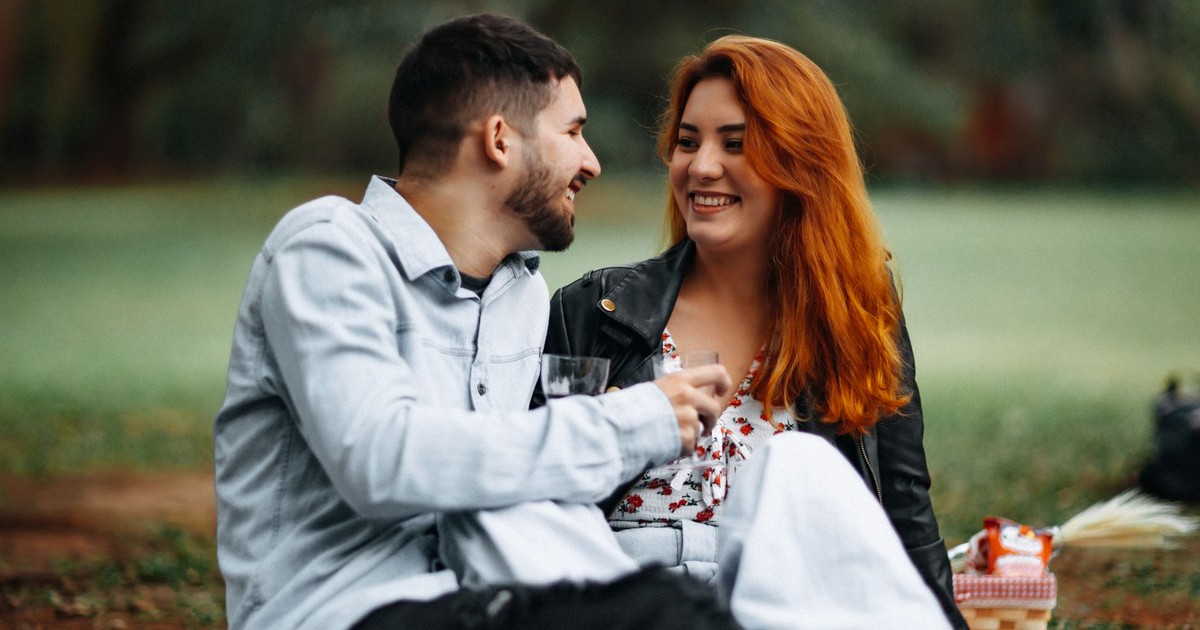 Happy couple enjoying a romantic picnic outdoors with wine and smiles.