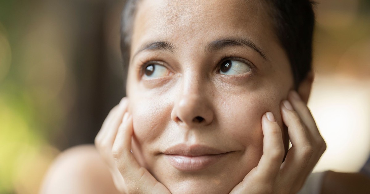 A serene portrait of a woman looking contemplatively upwards, captured outdoors with soft lighting.