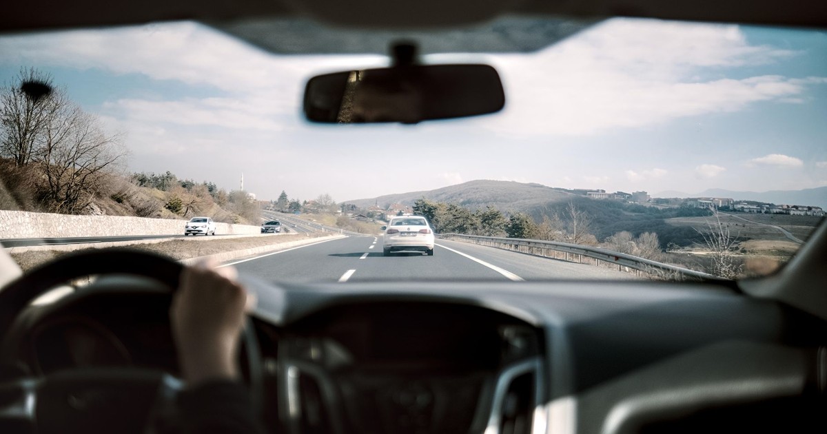 View from a car driving down a scenic highway with hills in the background, depicting a casual road trip.