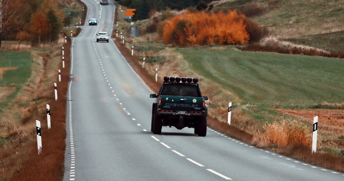 Pickup truck driving on a winding road in Huskvarna, Sweden, during autumn.