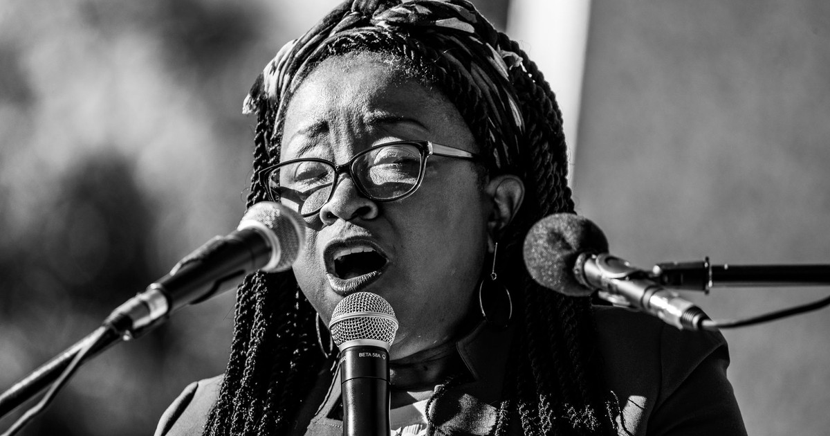 Black and white portrait of an African American woman singing into a microphone, exuding passion and emotion.