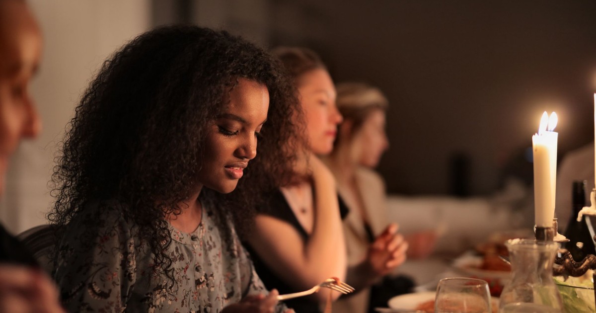 A diverse group enjoying a cozy, candlelit dinner together indoors.