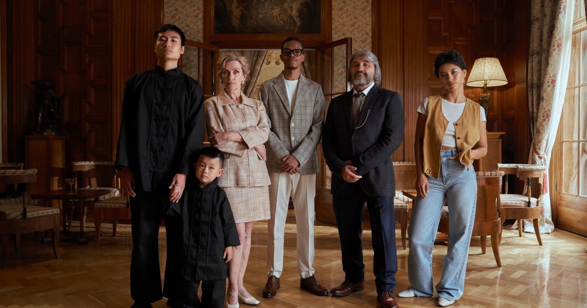 A diverse family poses together in a luxurious indoor setting, showcasing generational and cultural richness.