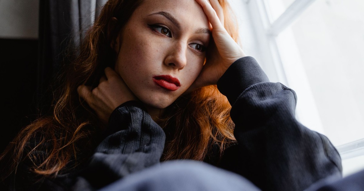 A young woman with a thoughtful expression gazes out the window in a moment of introspection.