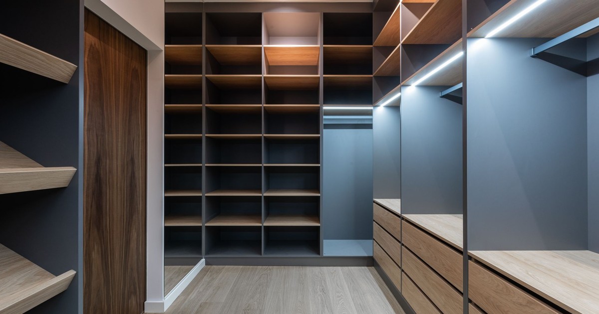 Interior of modern spacious wardrobe room with empty shelves near door and mirror