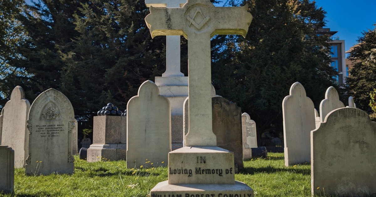 A serene view of gravestones in a historic London cemetery on a sunny day.