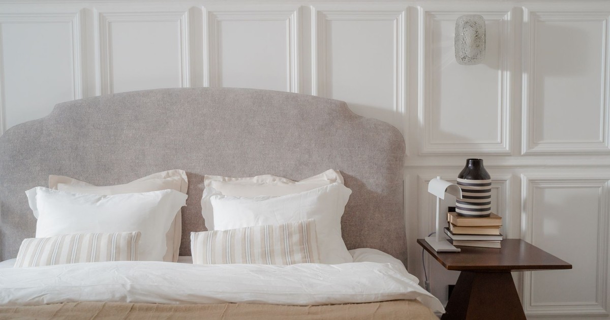 Elegant bedroom with cozy bed and stylish side table. Features neutral tones and soft lighting.