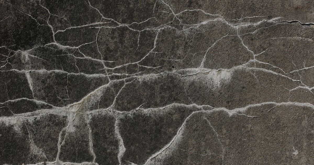 Detailed close-up of a cracked concrete wall texture, perfect for backgrounds and design elements.