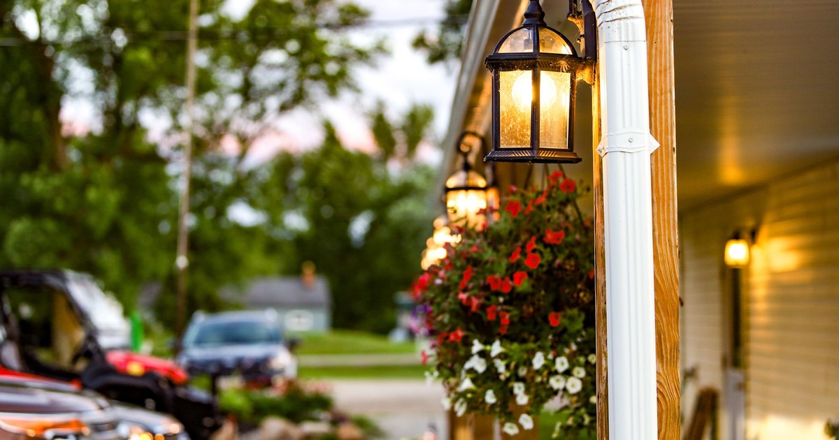 Charming illuminated porch with hanging flower baskets at dusk, creating a warm and inviting atmosphere.