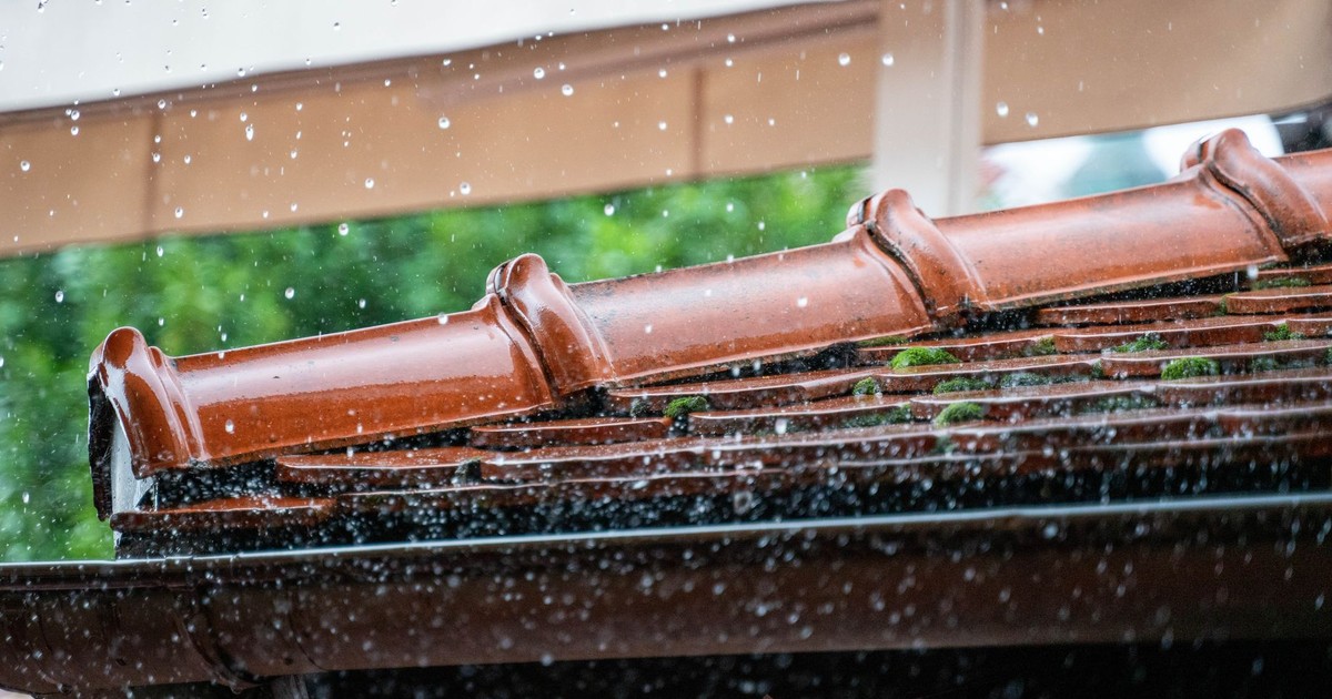 Detailed view of rain droplets cascading off a terracotta roof, capturing the essence of a rainy day.
