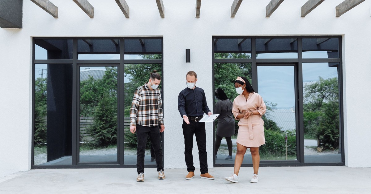 Real estate agents showing a house while maintaining safety protocols with face masks.