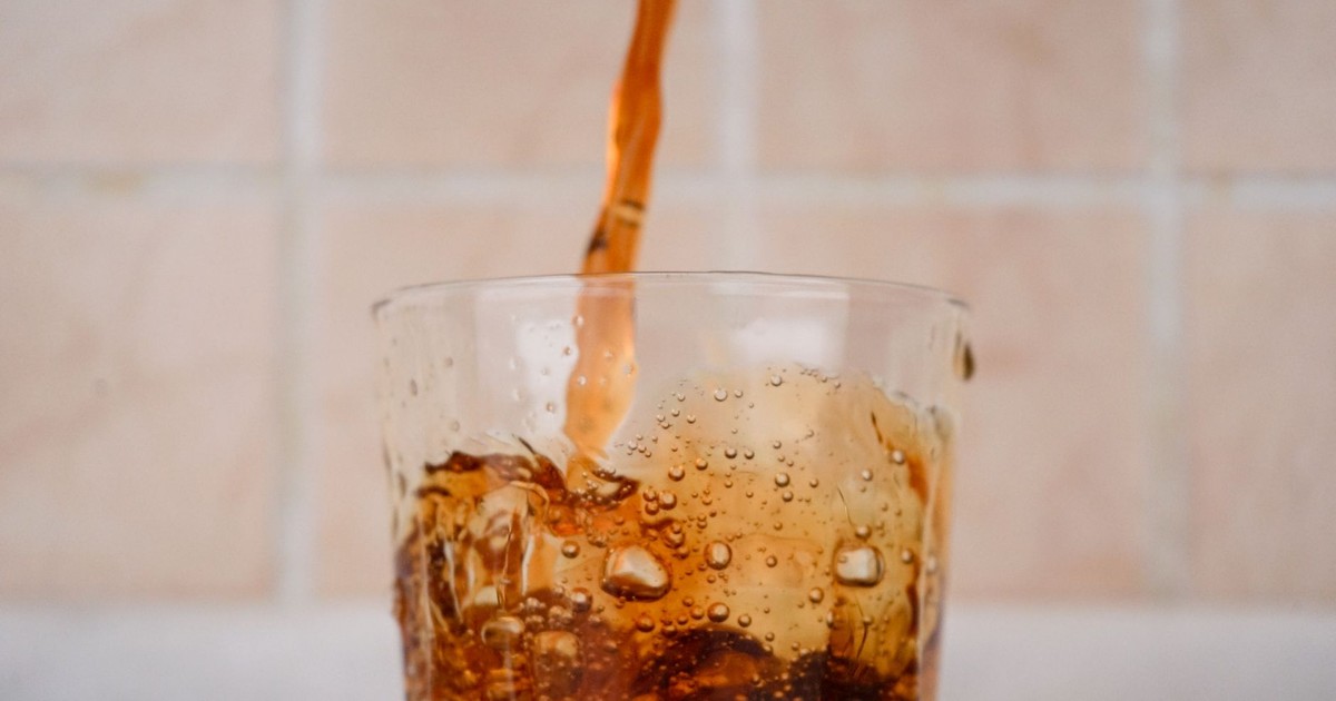 A close-up capture of soda being poured into a glass, creating a splash effect.