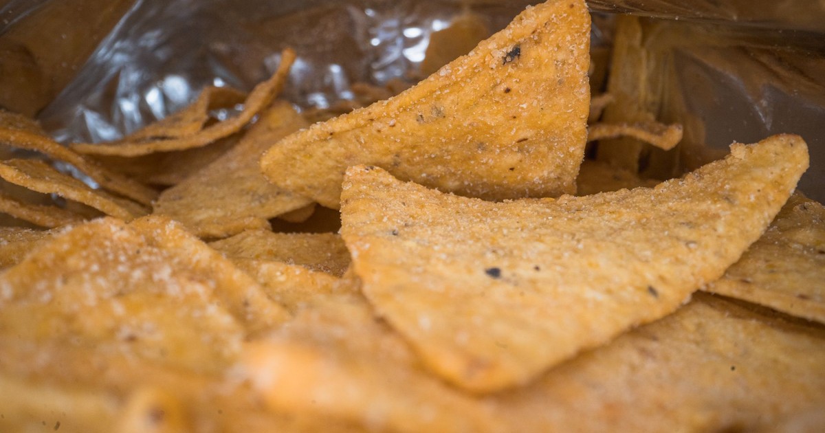 Macro shot of salted tortilla chips inside an open bag, showcasing texture.