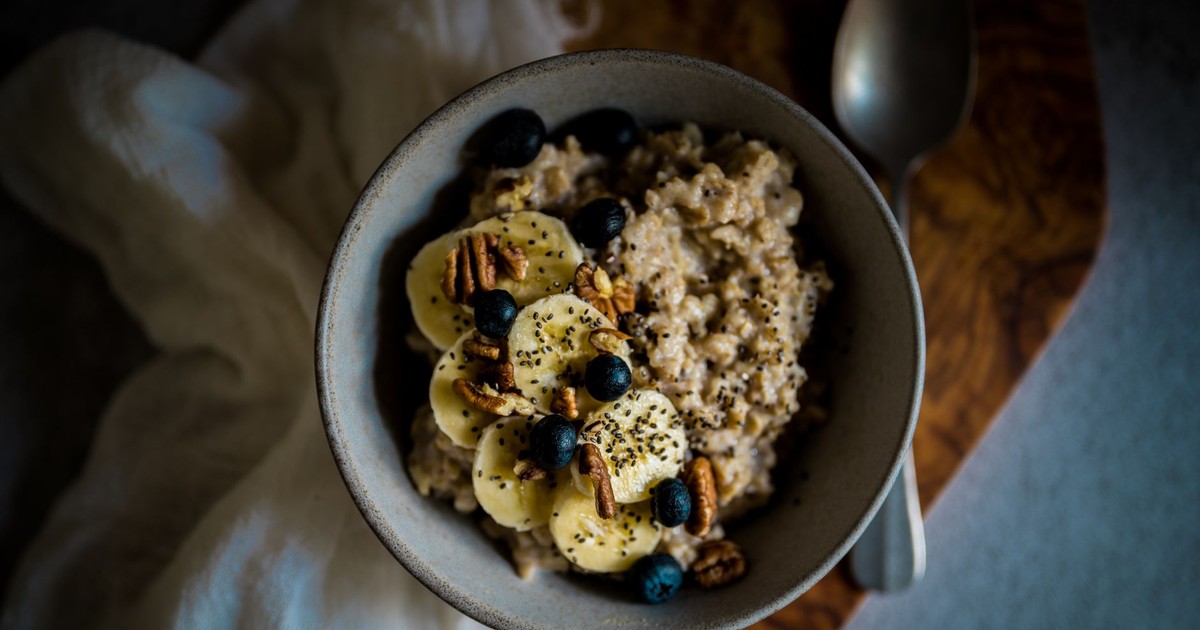Delicious oatmeal topped with bananas, blueberries, pecans, and chia seeds in a cozy setting.