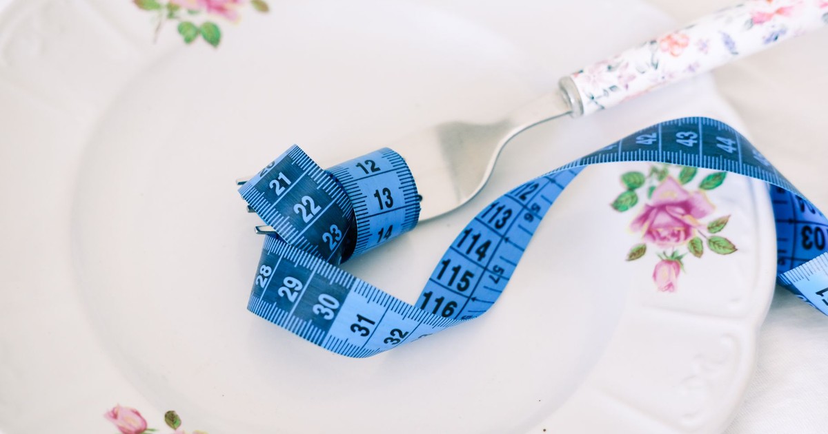A floral plate with a fork and blue measuring tape symbolizing dieting or healthy eating.
