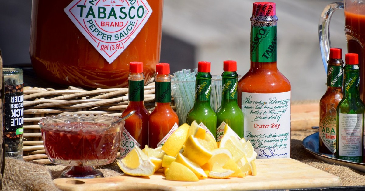 A vibrant display of Tabasco sauce bottles, lemon slices, and spices on a wooden board.