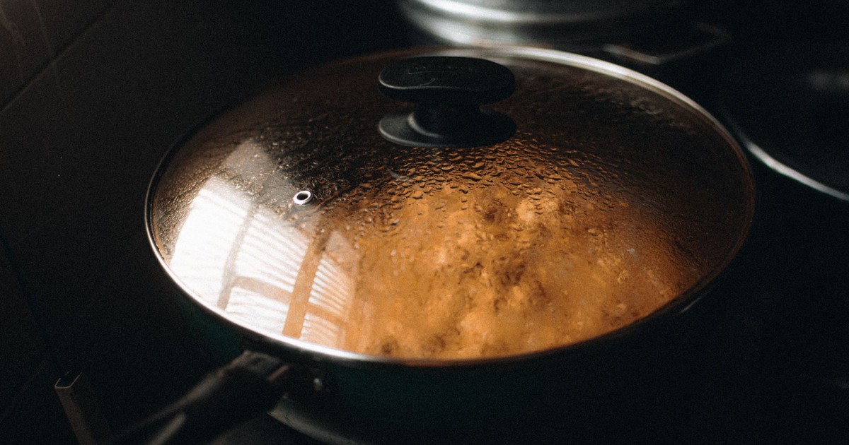Close-up of a steaming lidded pan on a stovetop, illustrating home cooking ambiance.