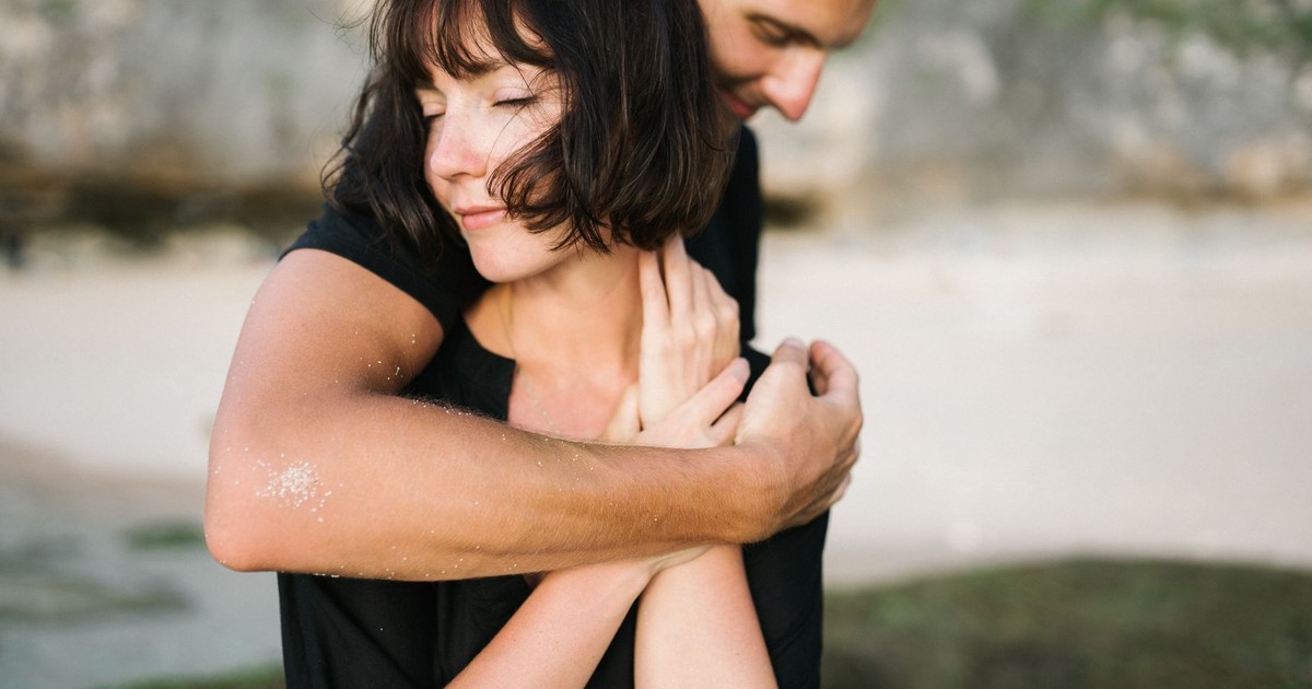 A couple embracing lovingly on a serene beach, capturing a moment of romance and connection.