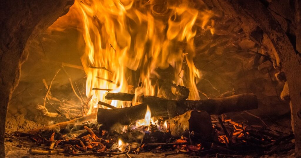 Cozy close-up of a bright fire burning in a traditional brick oven.
