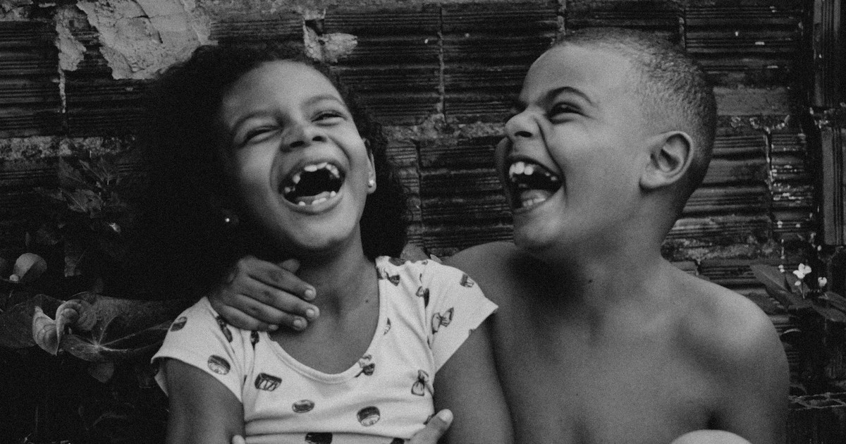 Black and white close-up of two children laughing joyfully together