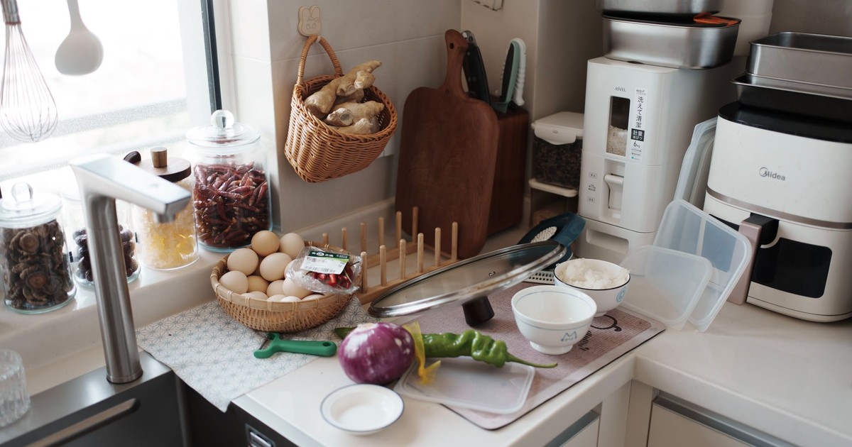 A kitchen counter with fresh ingredients ready for cooking, featuring eggs, vegetables, and kitchen gadgets.