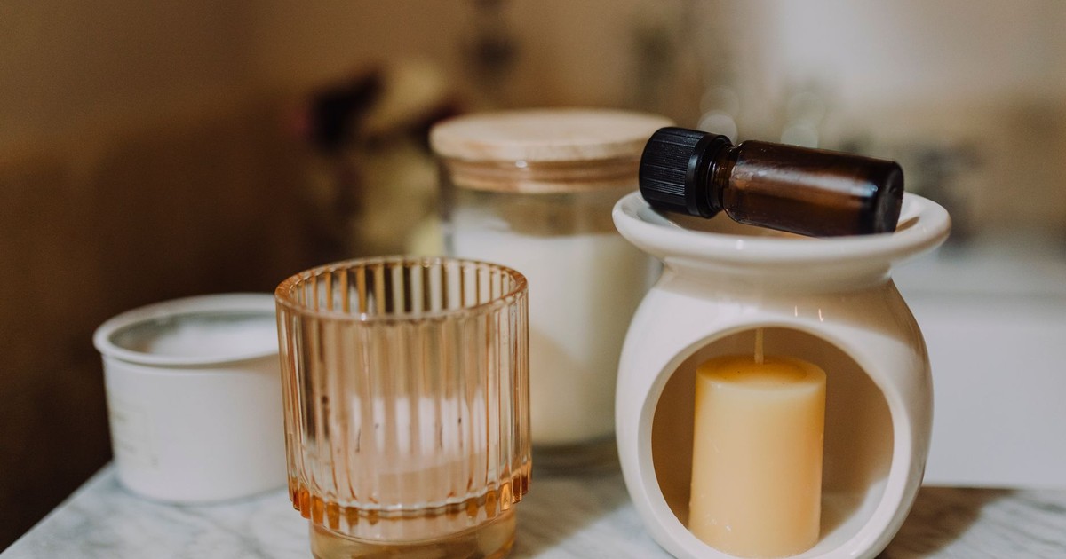 A serene aromatherapy arrangement with candles, glass jars, and essential oil on marble.