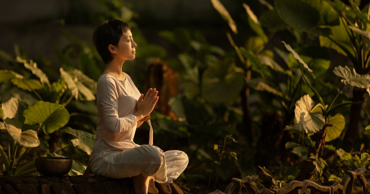 Serene scene of a woman meditating in a lush garden setting at daylight.