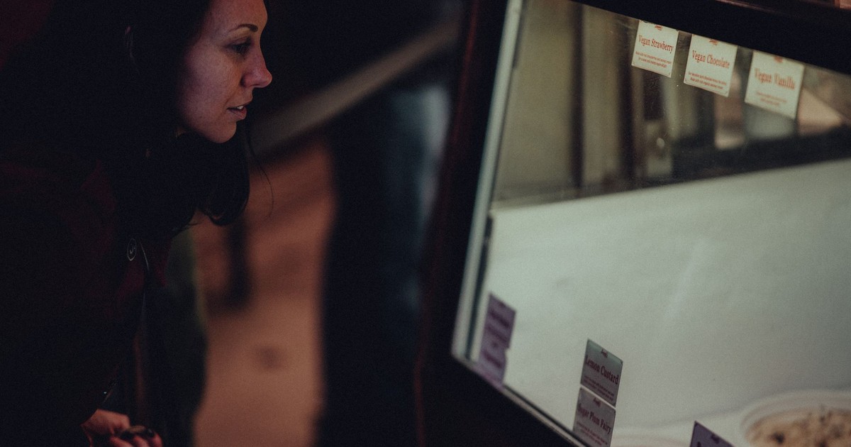 A woman peers into a store display case, considering her shopping options.
