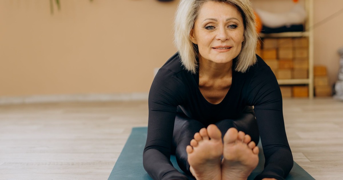 Elderly woman doing yoga indoors, promoting wellness and positive aging.