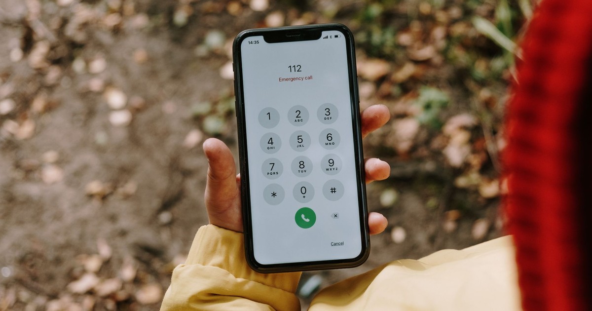 Close-up of a smartphone displaying emergency number 112 outdoors.
