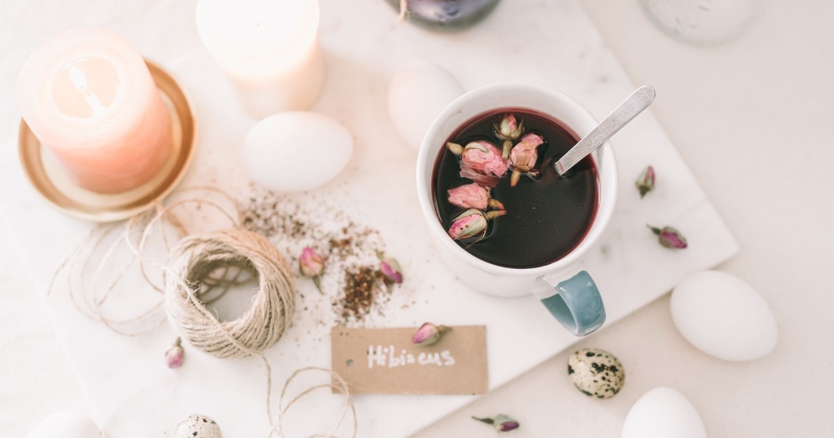 A serene flatlay featuring hibiscus tea, candles, and eggs, perfect for spring celebrations.