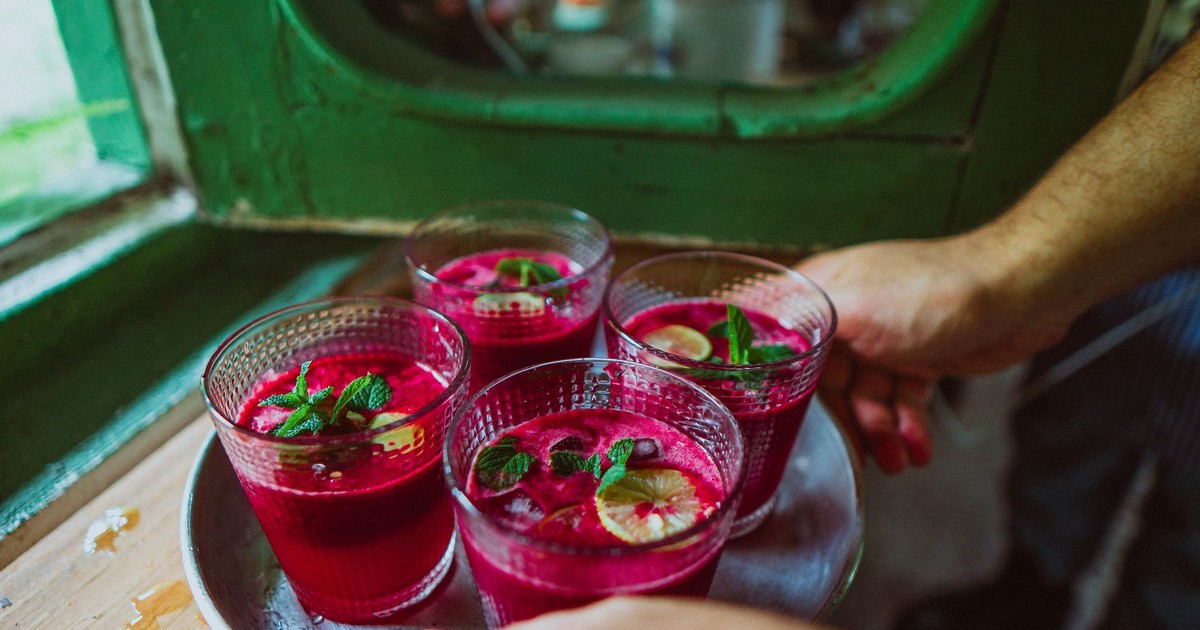 Refreshing beet juice garnished with lemon and mint, served on a tray indoors.