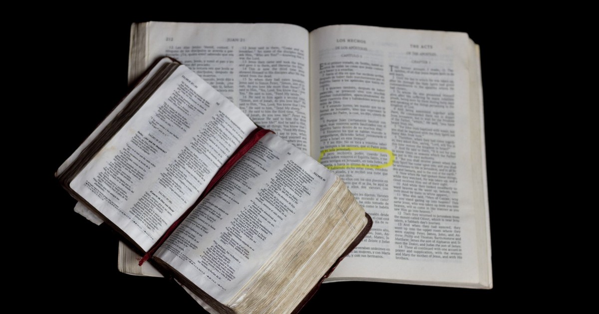 An open Bible on top of another against a plain black background.