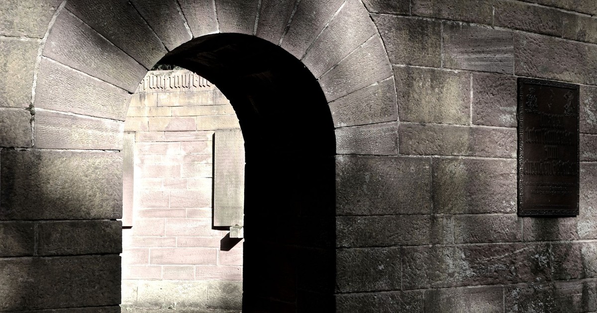 Rustic stone archway with dramatic shadows depicting historic architecture.
