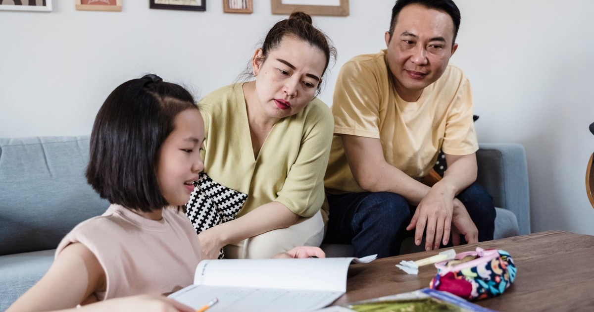 Parents assisting daughter with her homework in a cozy living room setting.