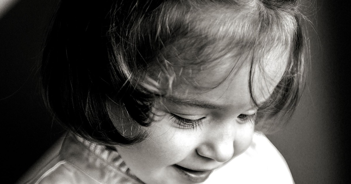 Heartwarming close-up black and white portrait of a smiling girl captured in soft lighting.