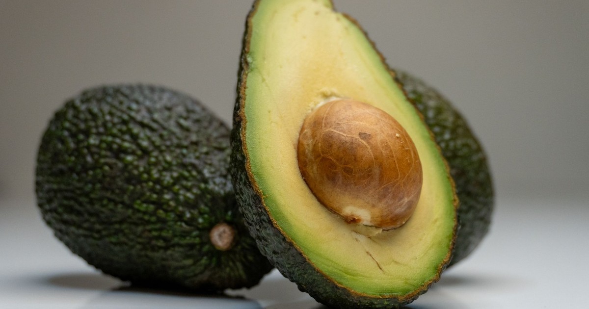 Close-up of fresh avocado halves against a gray background, highlighting their texture.
