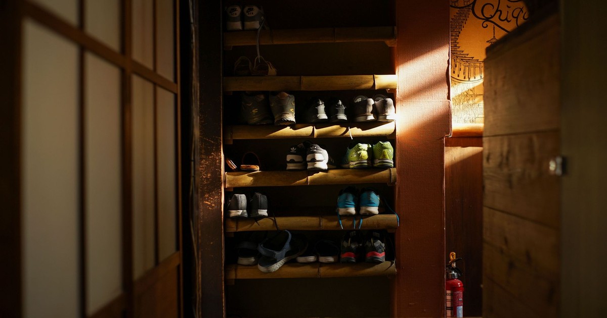 Warmly lit shoe rack featuring organized sneakers in a traditional Kyoto residence.