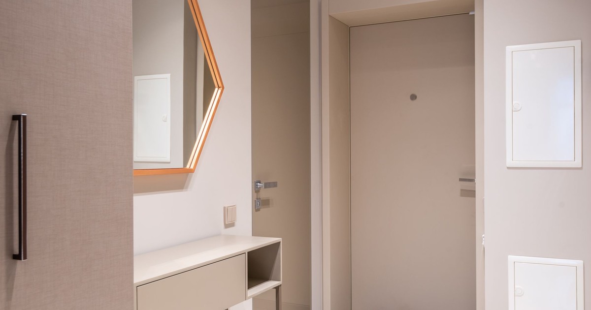 Contemporary corridor interior with beige doors and cabinet under hexagonal shaped mirror at home