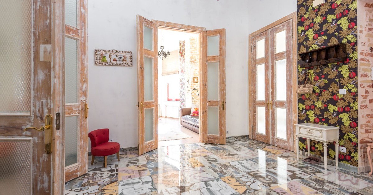 A vibrant, eclectic interior featuring colorful floors, wooden doors, and vivid wallpaper.
