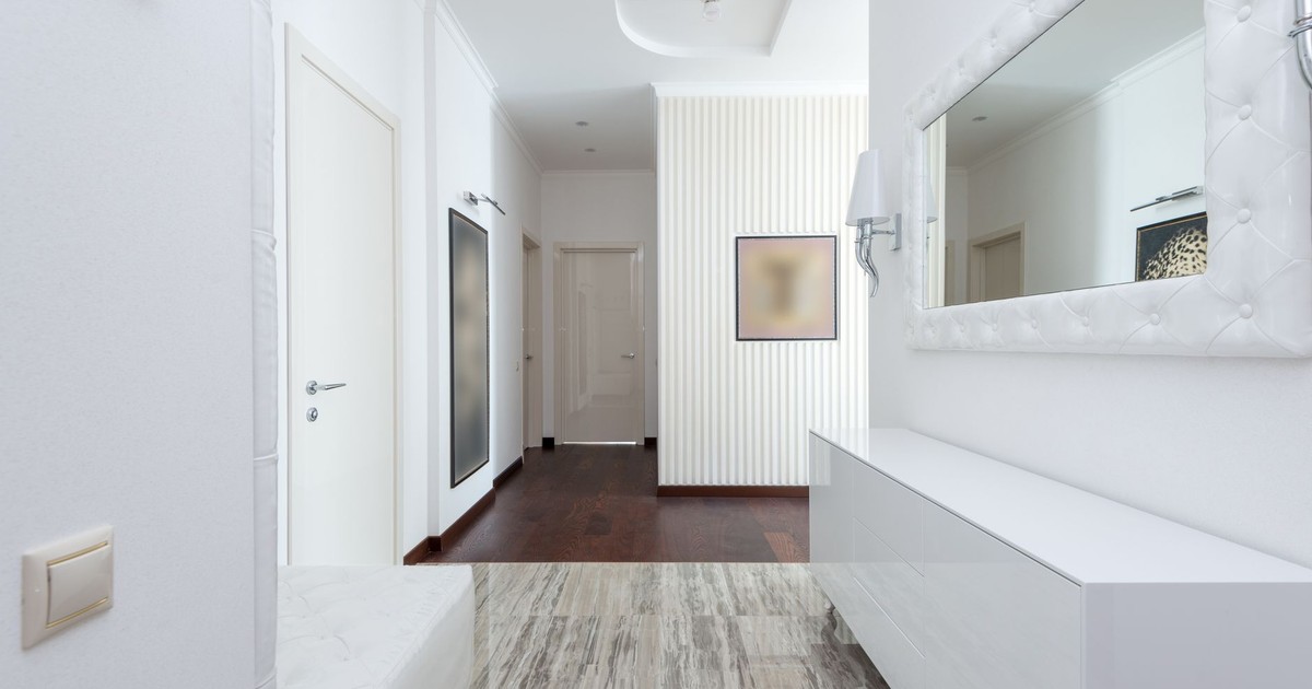 Bright corridor with contemporary design featuring white walls, minimal decor, and mirror.